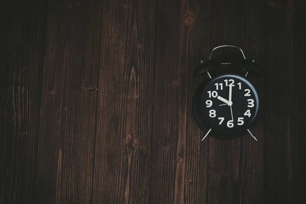 Reloj despertador negro vintage en mesa de madera oscura, hora y plazo —  Fotos de Stock