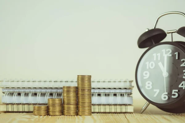 Pasos de pila de monedas con reloj despertador vintage y pluma, portátil —  Fotos de Stock