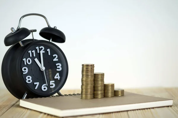 Pasos de pila de monedas con reloj despertador vintage y pluma, portátil —  Fotos de Stock