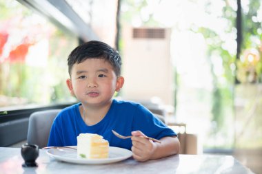 Pastanede ya da kafede pasta yiyen Asyalı çocuk..