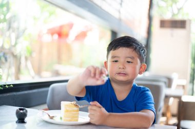 Pastanede ya da kafede pasta yiyen Asyalı çocuk..