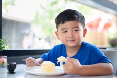 Pastanede ya da kafede pasta yiyen Asyalı çocuk..
