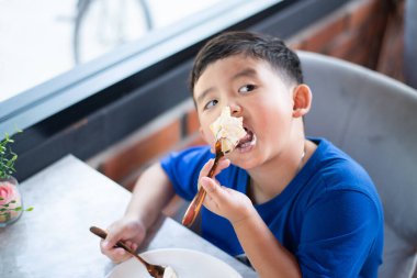 Pastanede ya da kafede pasta yiyen Asyalı çocuk..