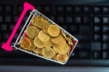 Online alışveriş, e-ticaret ve iş konsepti için bilgisayar ve klavyeli süpermarket arabasında madeni paralar