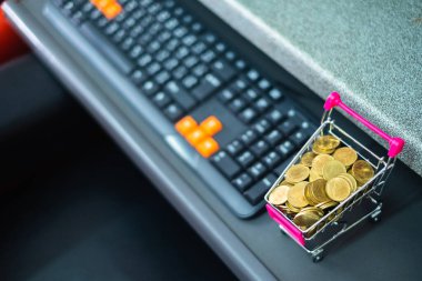 Online alışveriş, e-ticaret ve iş konsepti için bilgisayar ve klavyeli süpermarket arabasında madeni paralar