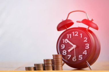 Alarm saati ve para basamaklarının çalışma masasındaki basamakları, tasarruf parası konsepti, bankacılık ve iş fikri zamanı.