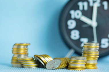 Çalar saati olan para yığınları kopyalama alanı, tasarruf parası kavramı, bankacılık ve iş fikri için zaman. Sığ odak.