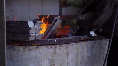 Fabrikada ağır çekimde metal parçaların ateşlenmesi, fabrikadaki fırında parçaların sertleşmesi, erkek işçinin ateş etmesi.  