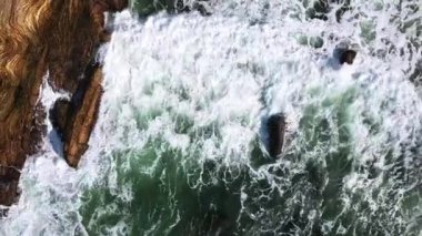 okyanus dalgası ve kayaların üst görünümü, Pasifik Okyanusu'nun kayalık kıyılarının havadan görünümü, Rocky Shore'a Doğru Koşan Dalgaların Havadan Vurulması, kayalara çarpan dalgaların havadan görünümü