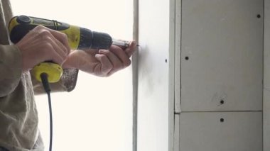 Vidaları tornavidayla sıkılaştırır, civataları alçıpan, tornavida ve alçıpan ile sıkar inşaat işçisi duvarı tamamlar, Sanding Alçıpan, eski evleri onarmak için inşaat malzemesi kullanır.