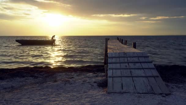 男は日没時にボートを係留男とボートのシルエット日没時に海の上に桟橋 — ストック動画