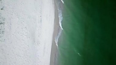 Kar beyazı bir plaj ve deniz sörfünün üst görüntüsü, kumsal ve deniz dalgalarının hava görüntüsü, kıyıya ulaşan okyanus dalgalarının hava aracı görüntüleri, turkuaz denizdeki güzel dalgaların hava aracı görüntüsü.