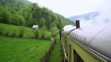 Eski bir tren vagonunun çatısından manzara, Romanya 'da eski bir buhar lokomotifi, buharlı dar ölçü treni, kırsal alanda tıkırdayan buhar treni, dar ölçülü demiryolu.