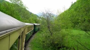 Eski bir tren vagonunun penceresinden manzara, Romanya 'da eski bir buhar lokomotifi, buharlı dar ölçü treni, kırsal alanda tıkırdayan buhar treni, dar ölçülü demiryolu.