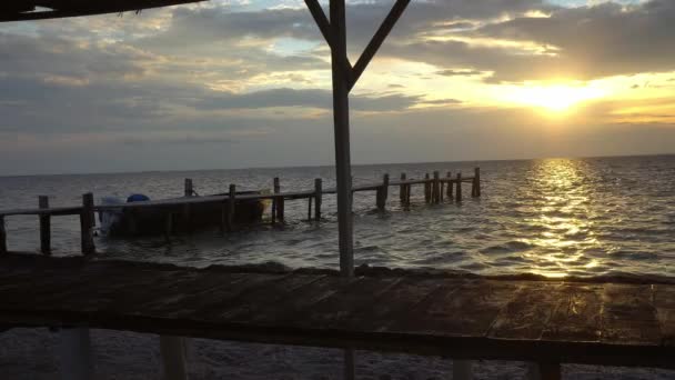 男は日没時にボートを係留男とボートのシルエット日没時に海の上に桟橋 — ストック動画