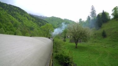 Eski bir tren vagonunun çatısından manzara, Romanya 'da eski bir buhar lokomotifi, buharlı dar ölçü treni, kırsal alanda tıkırdayan buhar treni, dar ölçülü demiryolu.,