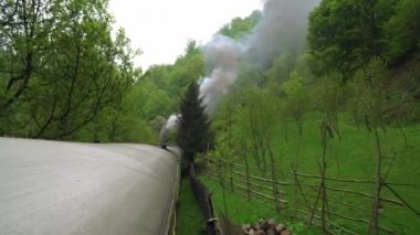 Eski bir tren vagonunun çatısından manzara, Romanya 'da eski bir buhar lokomotifi, buharlı dar ölçü treni, kırsal alanda tıkırdayan buhar treni, dar ölçülü demiryolu.,