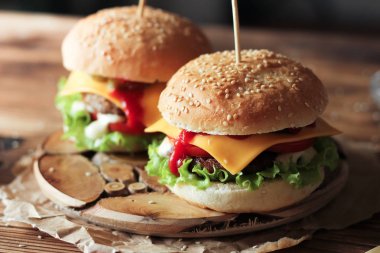 Sığır eti, salata ve ahşap masa üzerinde peynir ile iki el yapımı hamburger.