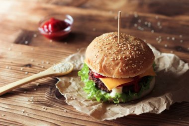 Sığır eti, salata ve ahşap masa üzerinde peynir ile iki el yapımı hamburger.