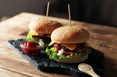 Sığır eti, salata ve ahşap masa üzerinde peynir ile iki el yapımı hamburger.