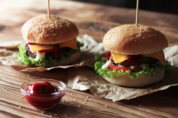 A marha-, saláta- és sajt, a fából készült asztal két kézzel hamburgerek. — Stock Fotó