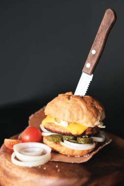 El yapımı burger beef, turşu, peynir ve ahşap tahta üzerinde bıçak.