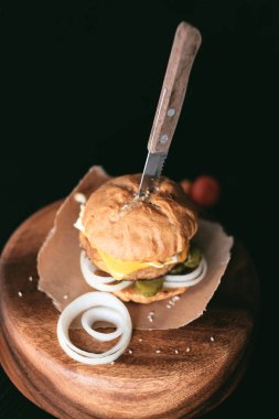 El yapımı burger beef, turşu, peynir ve ahşap masa üzerinde bıçak. 