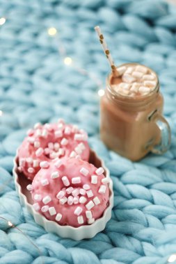 Hatmi ve mavi Merinos cam bardakta sıcak çikolata ile pembe çörek battaniye örgü. Arka plan ışığı