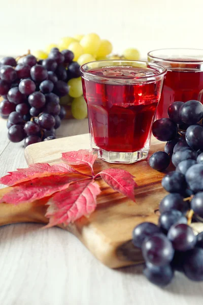 Два стакана виноградного сока со льдом и черным и зеленым виноградом — стоковое фото