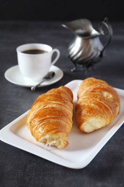 İki taze kruvasan ve kahve koyu arka plan üzerinde