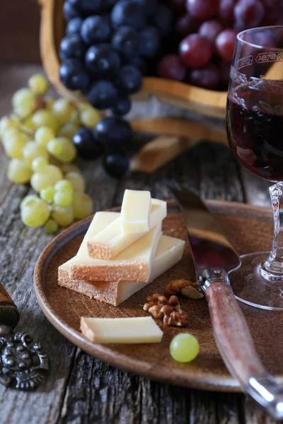 Uve nere e verdi, formaggi francesi, noci e bicchieri da vino — Foto Stock