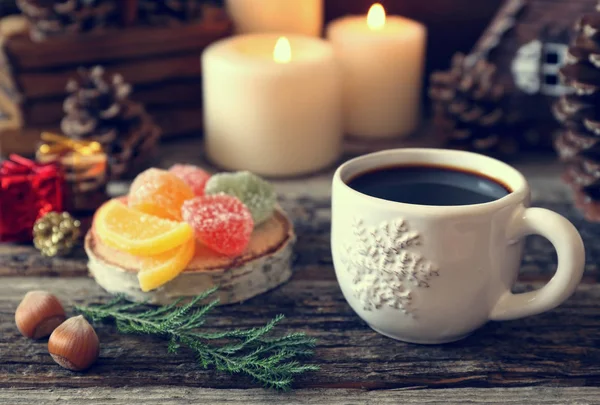 Чашка кофе, сосновые шишки, горящие свечи и красочные конфеты — стоковое фото