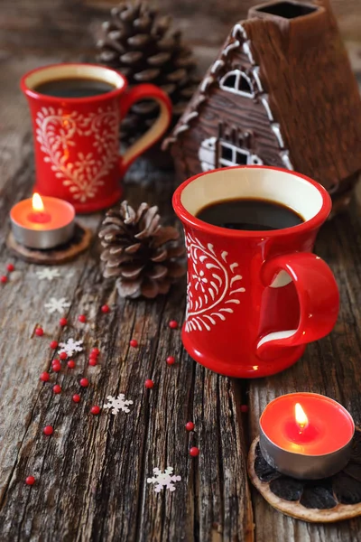 Dos tazas rojas de café, conos de pino y vela encendida — Foto de Stock