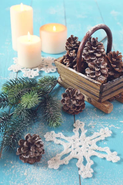 Floco de neve de malha, cones de pinho na cesta e vela ardente — Fotografia de Stock