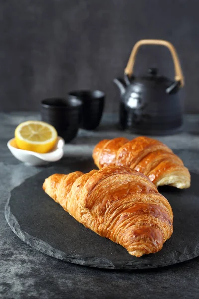 Two fresh croissants, lemon and teapot — Stock Photo, Image