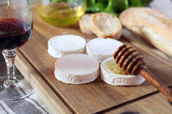 Jemný francouzský kozí sýr, chléb, med, hlávkový salát a sklenice na víno — Stock fotografie