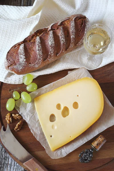 Maasdam チーズ、パン、ブドウ、白ワインのガラス — ストック写真