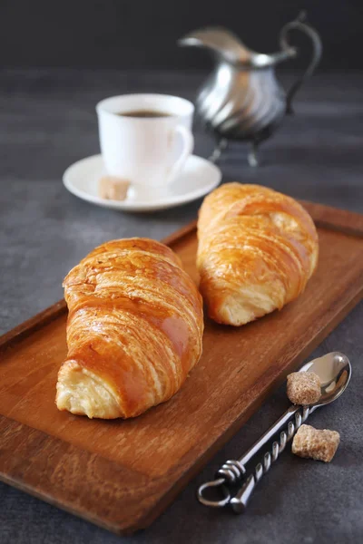 Two fresh croissants and cup of coffee on dark background — Stock Photo, Image