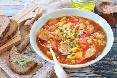 Patates, domates, sosis ve bir dilim ekmek ile ev yapımı baharatlı bezelye çorbası. Kırsal biçim