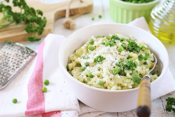 İtalyan mutfağı. Risi e bisi, Venedik mutfağı. Yeşil bezelyeli yeşil bezelyeli risotto tabağı, rendelenmiş parmesan peyniri, zeytinyağı ve açık arkaplanda maydanoz.