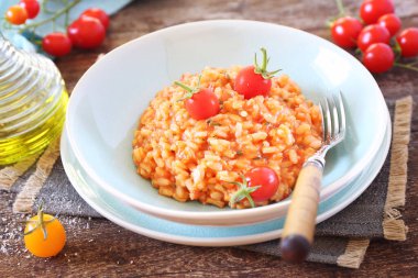 İtalyan mutfağı. Domates pilavı, zeytinyağı ve ahşap zemin üzerinde kiraz domatesleri.