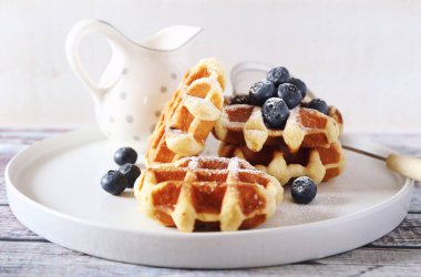 Hafif arkaplanda tatlı kahvaltı için yabanmersinli geleneksel Belçika waffle 'ları.