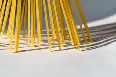 Spagetti dikey olarak beyaz bir backgr üzerinde güneş ışığı altında duruyor.