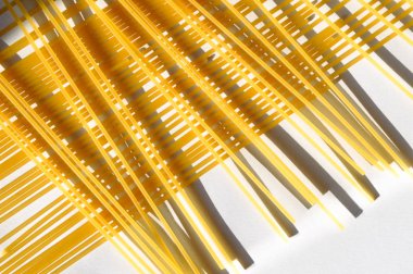 Güneş ışığı altında beyaz bir arka plan üzerinde çapraz desen spagetti