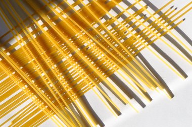 Güneş ışığı altında beyaz bir arka plan üzerinde çapraz desen spagetti