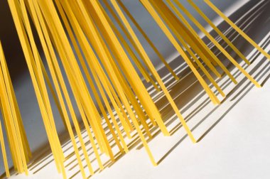 Spagetti dikey olarak beyaz bir backgr üzerinde güneş ışığı altında duruyor.