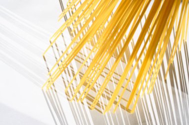 Spagetti dikey olarak beyaz bir backgr üzerinde güneş ışığı altında duruyor.