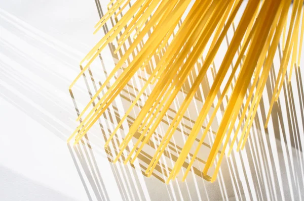 Spagetti dikey olarak beyaz bir backgr üzerinde güneş ışığı altında duruyor.