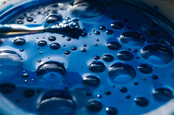 Oil blue paint with big bubbles in a round container in the sun. — Stock Photo, Image