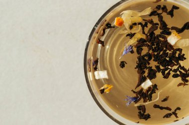 Siyah çay yaprakları bir saydam mavi çiçekler, portakal kabuğu ile